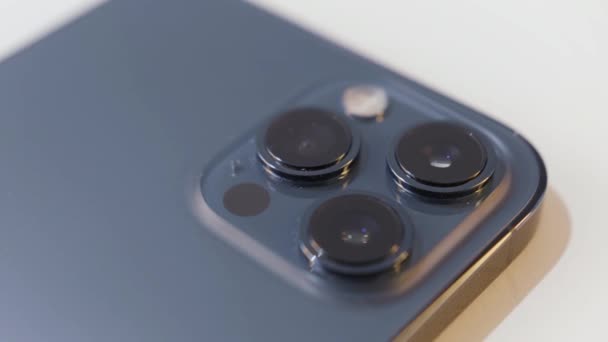 Närbild detaljer om en vacker mörkblå smartphone med tre kameror. Börja. Begreppet modern teknik och design, enhet isolerad på vit bakgrund. — Stockvideo