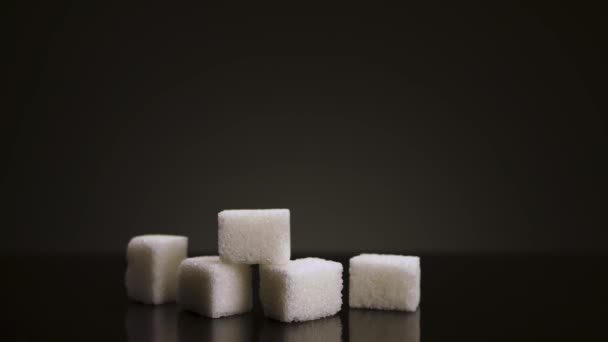 Närbild av växande högen av sockerbitar isolerad på mörkgrå bakgrund. Lagerbilder. Stoppa rörelse effekt, begreppet socker öka konsumtionen. — Stockvideo