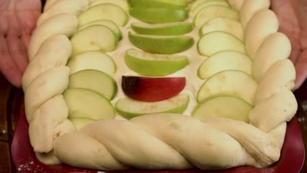 Proces van het maken van een appeltaart. Voorraadbeelden. Close-up van het koken smakelijk dessert, rauw gebak met appelschijfjes voor het bakken, vrouwelijke hand nemen een appelschijfje. — Stockvideo