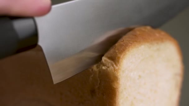 Tagliare il pane isolato su fondo grigio. Filmati delle scorte. Primo piano del taglio a mano di una pagnotta appena sfornata di pane bianco con un coltello affilato in acciaio, concetto di cibo. — Video Stock
