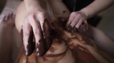 Güzeller güzeli kadın kaplıca salonunda çikolata masajı yaptırıyor. Başla. Erimiş sıcak çikolatayla dişiye masaj yapan erkek elleri, güzellik prosedürü kavramı..