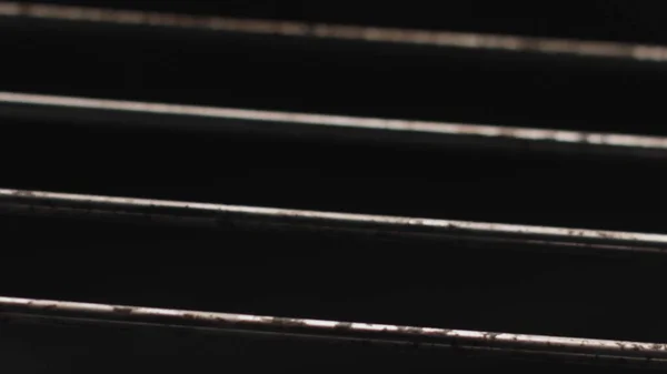Κοντινό πλάνο των μεταλλικών ράβδων μέσα στο φούρνο με ανοιχτή φωτιά. Στικ. Βρώμικες ράβδοι χάλυβα με λίπος απομονωμένο σε μαύρο φόντο με καυτή φλόγα. — Φωτογραφία Αρχείου