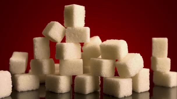 Zbliżenie wielu kostek cukru stojących na szczycie siebie odizolowanych na czerwonym tle. Materiał filmowy. Pojęcie słodyczy, słodyczy i żywności. — Wideo stockowe