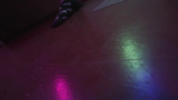 Luzes coloridas de festa noturna refletidas no chão. Imagens de stock. Movimentos de pé de dança no chão em casa em meias com desenhos incomuns em preto e branco. — Vídeo de Stock