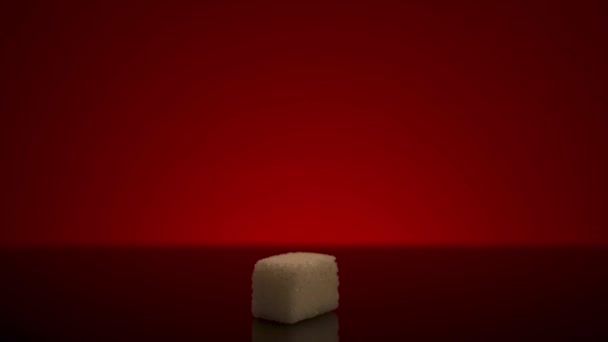Close-up van enkele witte blokjes suiker die op de tafel liggen, geïsoleerd op een rode achtergrond. Voorraadbeelden. Begrip verslaving aan zoete producten en gezondheidsproblemen. — Stockvideo