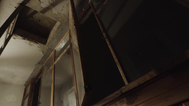 Una ventana móvil dentro de un balcón en mal estado en un barrio pobre. Imágenes de archivo. Vista inferior de un antiguo balcón interior con un cielo oscuro detrás de la ventana. — Vídeos de Stock