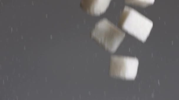 Primer plano de muchos cubos de azúcar blanco cayendo aislados sobre fondo gris. Imágenes de archivo. Concepto de dulces y diabetes. — Vídeos de Stock