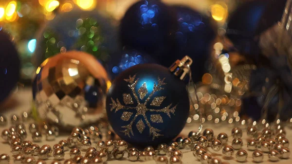 Juguetes de Navidad en el fondo de luces intermitentes festivos. Concepto. Vacaciones de Año Nuevo, primer plano de hermosa bola de juguete azul con un copo de nieve y guirnalda brillante. —  Fotos de Stock