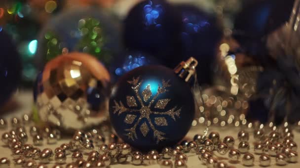 Giocattoli di Natale su sfondo luci lampeggianti festive. Concetto. Vacanze di anno nuovo, primo piano di bella palla giocattolo blu con un fiocco di neve e ghirlanda splendente. — Video Stock