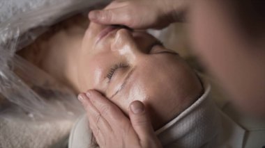 Salonda profesyonel yüz masajı. Başla. Masörlerin elleri profesyonelce hareket eder. Spa 'da yüz masajı tazeleniyor. Yüz masajından hoş duygular