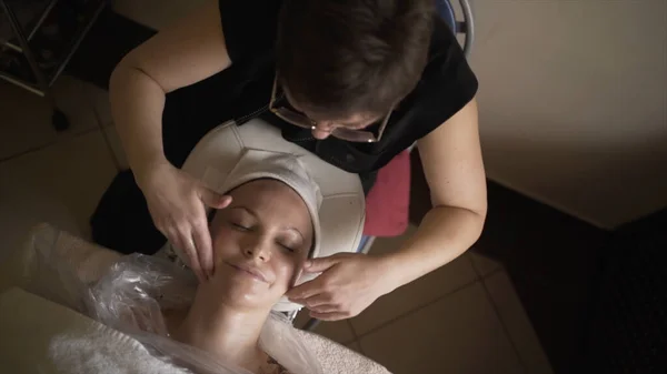 Professioneller Masseur gibt der Frau eine Gesichtsmassage. Handeln. Professionelle Gesichtsmassage im Spa. Angenehme und verjüngende Gesichtsmassage — Stockfoto