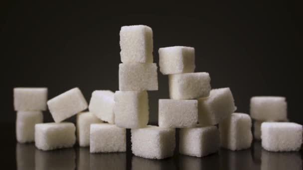 검은 배경에 분리 된 흰 설탕 덩어리. 자료 화면이요. 당뇨병과 비만에 대한 개념인 하얀 설탕 조각들을 클로즈업하는 모습. — 비디오