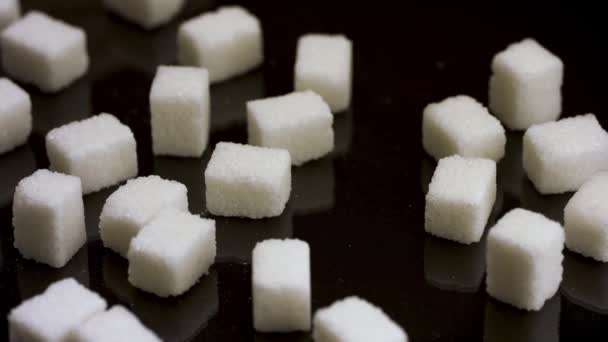 Крупним планом чистити половину цукрових кубиків від столу, відмовляючись від їжі цукерок та цукерок. Стокові кадри. Шматочки білого цукру ізольовані на чорному тлі . — стокове відео
