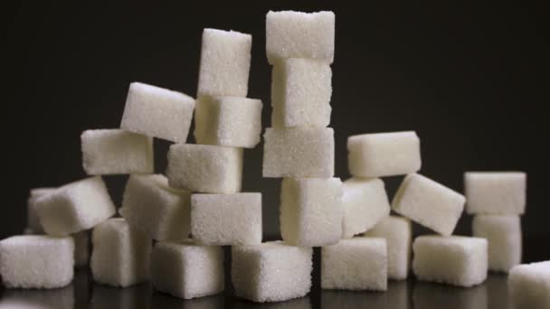 Sockerrör kuber isolerade på svart bakgrund. Lagerbilder. Närbild av pyramid gjord av vita kuber, begreppet sötsaker och konfektyrer. — Stockvideo