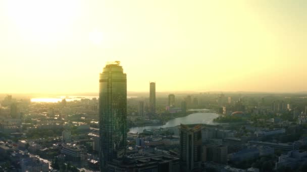 Vista aérea del centro de negocios Vysotsky y la ciudad de Ekaterinburg al atardecer. Imágenes de archivo. Hermoso paisaje urbano panorámico con muchos edificios en el fondo dorado del cielo. — Vídeos de Stock