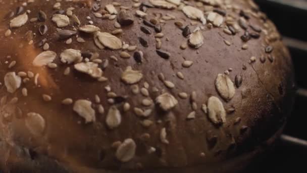 Preparations of rye bread in the oven with fire flame. Stock footage. Close up of freshly baked healthy bread with seeds and rolled oats isolated on black background. and — Stock Video