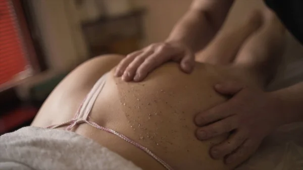 Μασάζ τρίψιμο των γλουτών στο Spa. Πάμε. Κοντινό πλάνο των επαγγελματικών κινήσεων του μασέρ κατά το τρίψιμο του σώματος. Διαδικασία τριψίματος για αναζωογόνηση και σύσφιξη του δέρματος — Φωτογραφία Αρχείου