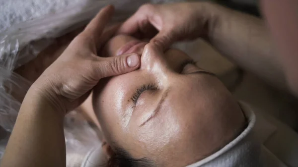 Manuelle Gesichtsmassagen für junge Frauen in Schönheitskliniken. Handeln. Massagetherapeutin arbeitet an Frauengesicht, Entspannungskonzept. — Stockfoto