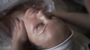 Güzellik kliniğindeki genç bir kadın için elle yüz masajı. Başla. Masaj terapisti kadın yüzü, rahatlama kavramı üzerinde çalışıyor.. 