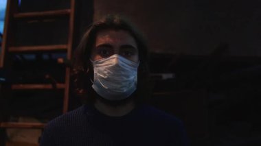 Ahşap merdivenin önünde koruyucu maske takan genç bir adamın portresi ve filmli bir ekran. Medya. Önleme kavramı Covid 19 salgını ve iş yerinde maske takmak.