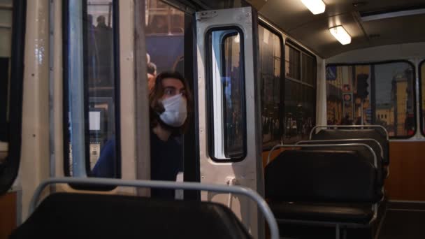 Молодой человек в защитной медицинской маске входит в автобусную выставку в музее транспорта. СМИ. Развлечения во время пандемии ковида 19. — стоковое видео