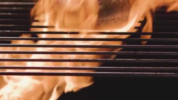 Bun on background of fire. Stock footage. Grain bread for hamburgers is grilled with fire. Loaf is cooked on fire in grill. Cooking Burger on barbecue grill. Hell of roast on grill — Stock Video