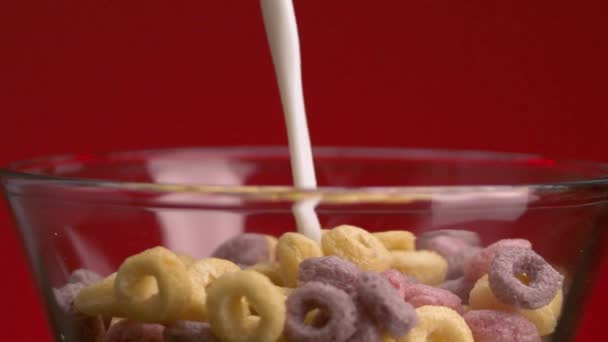 Νιφάδες με γάλα. Στικ. Κοντινό πλάνο σε πολύχρωμες γλυκές νιφάδες προσθέτουν γάλα. Γάλα με γλυκά πολύχρωμα δαχτυλίδια. Επιβλαβές γλυκό φαγητό — Αρχείο Βίντεο