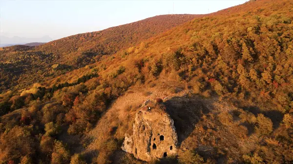 Egy ember áll a hegygerincen. Felvétel. Első látásra kinyújtott karokkal a sziklán. A szabad ember boldogan mászik hegyi párkányra gyönyörű kilátással. Felmászni a hegyre a napsütéses őszi napon — Stock Fotó