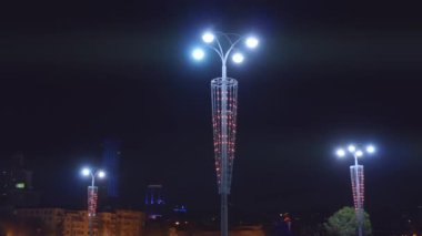 Gece vakti karanlık gökyüzü arka planında şehir caddesini aydınlatan güzel fenerler. Stok görüntüleri. Renkli ışıklandırmalı sokak lambaları, şehir dekorasyonu.. 