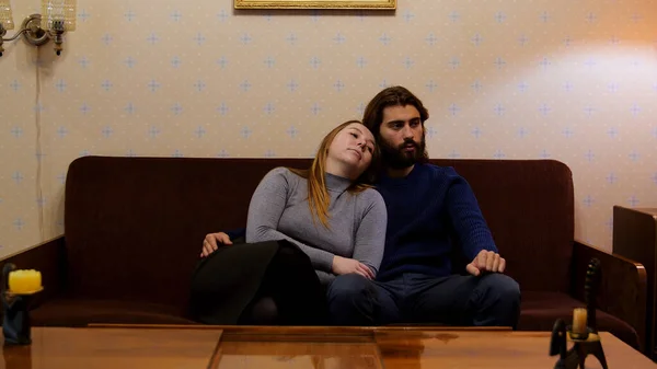 Portrét mladého sovětského páru, jak se dívá na televizi na gauči. Média. Muž a žena žijící v typickém bytě SSSR se staromódním nábytkem. — Stock fotografie