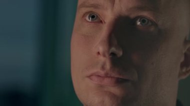 Kılsız, yakışıklı, yeşil gözlü ve bulanık arka plana bakan bir erkek yüzü. Stok görüntüleri. Kafkasyalı kel adam konsantre görünüyor..