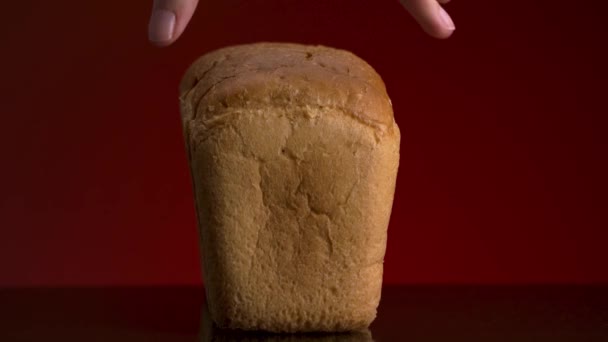 Κοντινό πλάνο νόστιμο ψημένο ψωμί φέτες με τραγανή κρούστα που βρίσκεται σε ανακλαστική επιφάνεια που απομονώνονται σε κόκκινο φόντο. Στικ. Αρσενικό χέρι παίρνει αργά ένα κομμάτι κομμένο άσπρο ψωμί καρβέλι. — Αρχείο Βίντεο