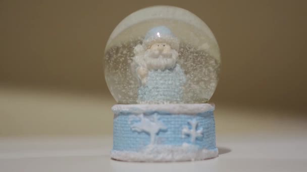 Primo piano di globo di neve ricordo con un Babbo Natale all'interno. Concetto. Bella palla di vetro con una figura di Babbo Natale e fiocchi di neve cadenti. — Video Stock