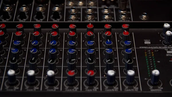 Sound producer hand is using a music mixer with editing tools. Media. Close up of male hand turning levers of a mixing console, concept of music production.