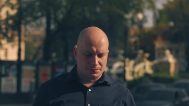 Close up of a hairless handsome male face with green eyes looking up on blurred street background. Stock footage. Bald caucasian man looking concentrated. — Stock Video