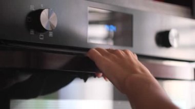 Kadın elinin modern bir yemek fırını, mutfak gereçleri açmasına yakın çekim. Kavram. Pişirme sürecinin ayrıntıları, fırının içine yemek kabı koymak..