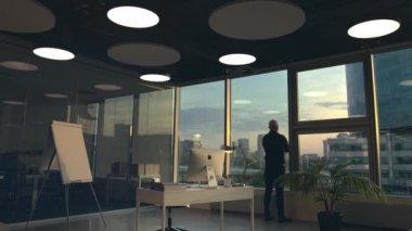 Stockholm - İsveç, 10.10.10.2020: Düşünceli iş adamı gökdelendeki modern ofisinden şehir manzarasına bakıyor. Stok görüntüleri. Yeni Apple Mac bilgisayarı modern bir ofisin içinde ve...