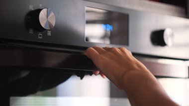 Kadın elinin modern bir yemek fırını, mutfak gereçleri açmasına yakın çekim. Kavram. Pişirme sürecinin ayrıntıları, fırının içine yemek kabı koymak..