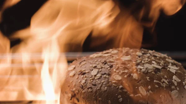 Zubereitung von Roggenbrot im Ofen mit Feuerflamme. Archivmaterial. Großaufnahme von frisch gebackenem gesundem Brot mit Samen und Haferflocken isoliert auf schwarzem Hintergrund. und — Stockfoto