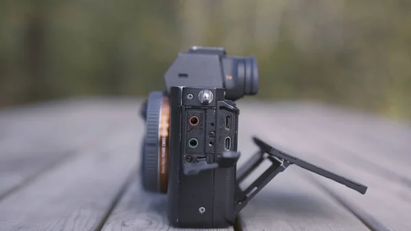 Close-up zijaanzicht van een moderne professionele fototoestel liggend op een houten bank. Actie. Concept van opnameapparatuur, roterende schermcamera. — Stockfoto