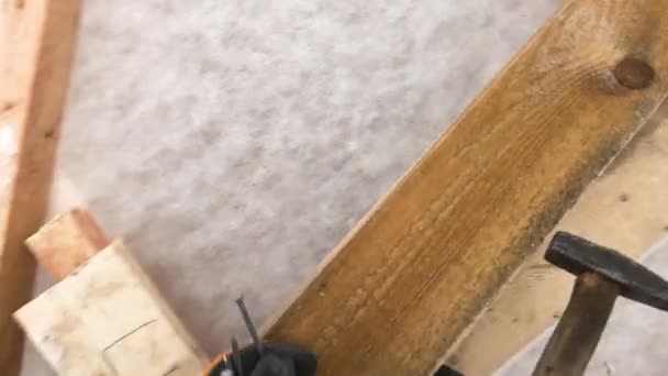 Man drives nails into wooden frame. Clip. Man with hammer drives nails into wooden Board. As carpenter works with wood frames in winter. First-person shooting — Stock Video