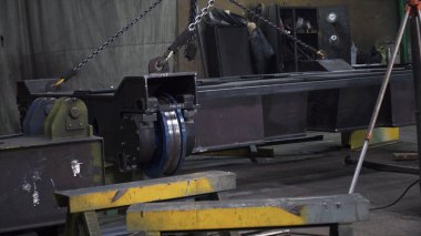 Metal yapı fabrikada zincirlerle kaldırılır. Şarjör. Metal taşıma iskeleti zincirlerle kaldırılır. Makine üretim tesisi