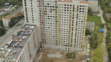 Yazın şehir ve gölün arka planında yapım aşamasında olan bina. Stok görüntüleri. Modern şehrin çok katlı binasının en üst manzarası.