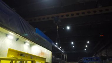 Metal kiriş fabrikada zincirlerle taşınır. Şarjör. Zincirlere asılmış çelik kiriş fabrikada sürüklenir. Zincirlerdeki askıdaki kiriş fabrikanın etrafında hareket ediyor