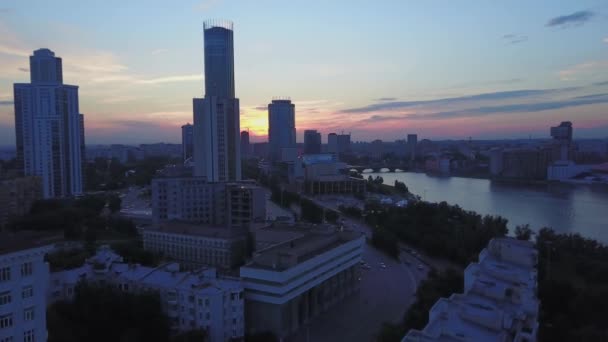 Vista aérea de la puesta de sol sobre los rascacielos y otros edificios. Imágenes de archivo. Tarde noche en un barrio soleado y moderno de la ciudad. — Vídeos de Stock