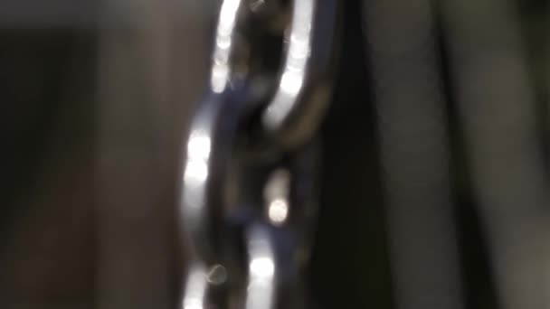 Silný řetěz spojený dohromady vyjadřující spojitost. Akce. Detailní záběr pohybujícího se stříbrného kovového řetězu na pozadí dětského hřiště. — Stock video