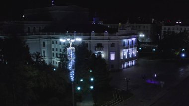 Modern gece şehrinde fenerlerle aydınlatılmış eski bir bina. Stok görüntüleri. Geceleri modern şehrin merkezindeki aydınlık eski binanın üst manzarası. Yaz gecelerinde şehrin eski binasında güzel fenerler