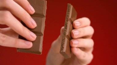 Çikolata kıran adam. Stok görüntüleri. Çikolatayı iki parçaya ayıran ellerin yakın çekimi. Lezzetli çikolata, izole edilmiş arka planda parçalara ayrılır.