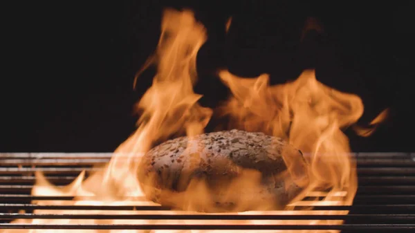 Bun auf Hintergrund des Feuers. Archivmaterial. Getreidebrot für Hamburger wird am Feuer gegrillt. Laib wird auf dem Grill gegrillt. Kochen Burger auf Grill. Hölle vom Grill — Stockfoto