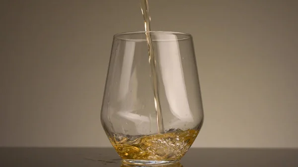 Close-up van gele vloeistof die in doorzichtig glas wordt gegoten. Voorraadbeelden. Gele drank wordt op geïsoleerde achtergrond in doorzichtig glas gegoten. Bier in helder glas — Stockfoto